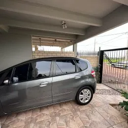 Foto externa mostrando um carro estacionado em uma área pavimentada.