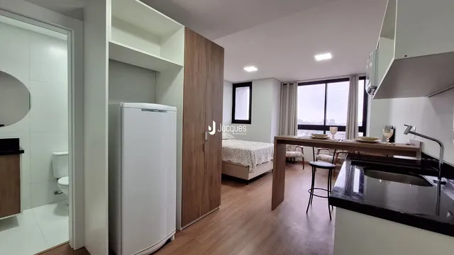 A sala de estar exibe um ambiente com piso de madeira e uma grande janela.