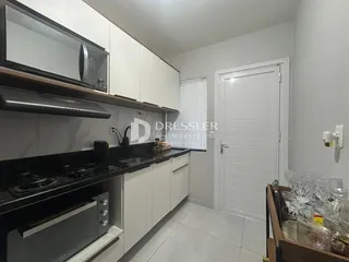 Vista da cozinha com armários brancos e bancadas escuras.