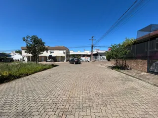 Vista externa de uma propriedade com área pavimentada e vegetação.