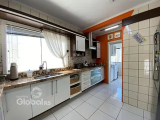 Vista da cozinha com armários brancos e bancada clara.
