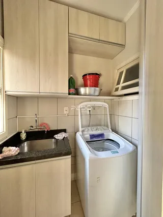 Interior de uma cozinha com armários superiores e máquina de lavar roupa visíveis.