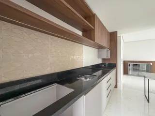 Uma cozinha com armários de madeira e bancada escura.