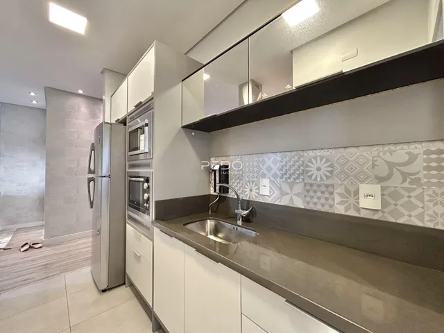 Cozinha moderna com armários brancos e revestimento decorativo.