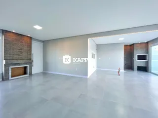 Ambiente amplo com piso claro e lareira de tijolos aparentes em uma sala de estar.