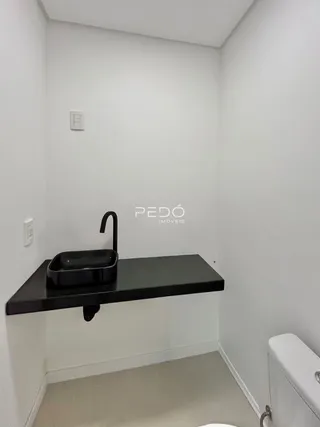 Foto de um ambiente interno com bancada escura e pia.