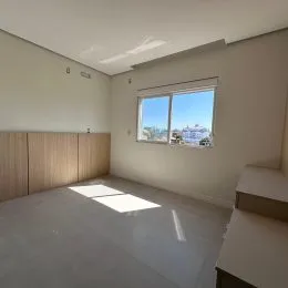 Foto de uma sala com paredes brancas e uma grande janela.