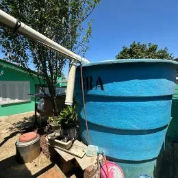 Um tanque cilíndrico azul está visível ao ar livre na propriedade.
