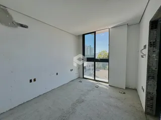 Interior de um cômodo com paredes brancas e piso de concreto.