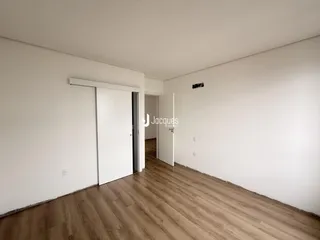 Vista interna de um ambiente com piso de madeira clara e paredes brancas.