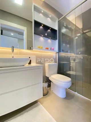 Banheiro moderno com bancada branca e box de vidro.