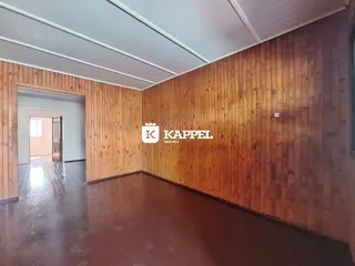 Sala de estar com revestimento de madeira nas paredes e piso de madeira.