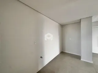 Vista interna de um corredor com paredes brancas e piso cinza claro.