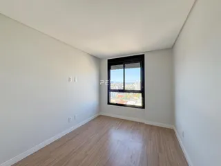 Ambiente interno com piso de madeira e vista da cidade através da janela.