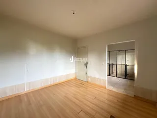 Interior de uma sala com piso de madeira e porta de acesso a outro cômodo.
