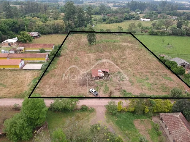 Vista aérea de um terreno aberto com vegetação e estrada de terra.