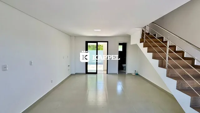 Hall de entrada com piso claro e escadaria de madeira em um ambiente moderno.