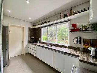 Vista da cozinha com armários brancos e bancadas de granito.