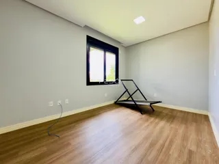 Ambiente interno de uma sala com piso de madeira e grande janela.