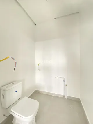 Foto de um ambiente interno mostrando um vaso sanitário e o piso cru.