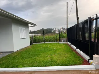 Fachada de uma casa com jardim gramado e cerca preta.