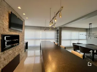 Ambiente moderno de sala de estar e jantar com ilha de cozinha em Lajeado.