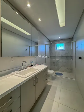 Banheiro moderno com box de vidro e revestimento em mármore.