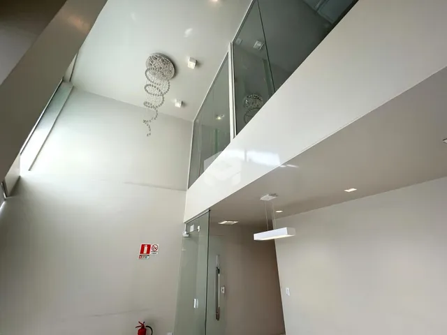 Vista interna de um espaço com pé direito alto e paredes brancas.
