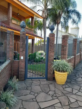 Fachada de uma propriedade em Lajeado, Brasil, com muro de tijolos e portão de ferro.