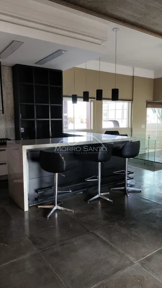 Cozinha moderna com ilha central e banquetas escuras.