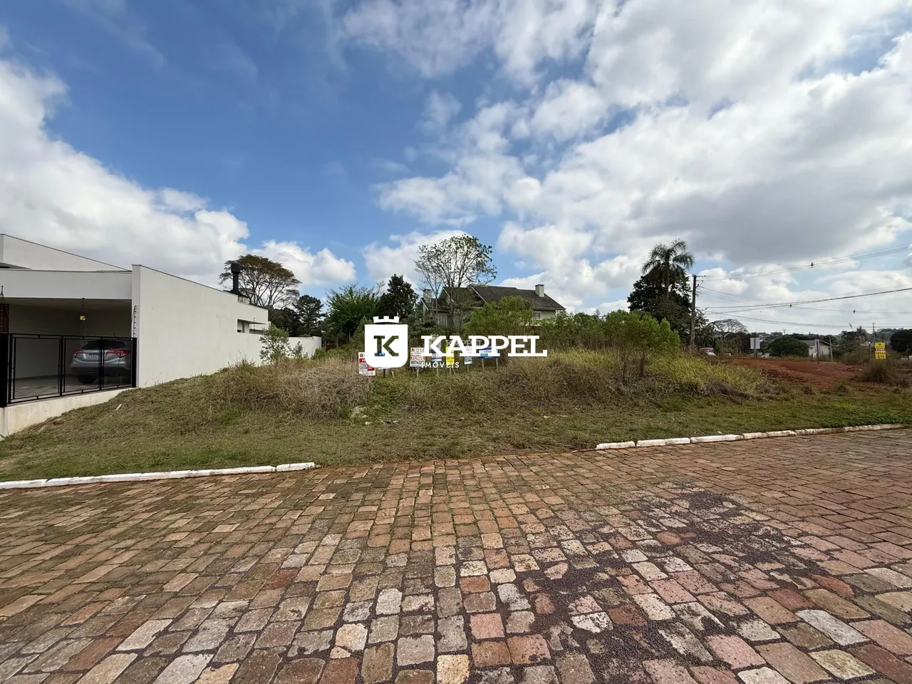 Vista externa de uma propriedade com um terreno gramado em primeiro plano.