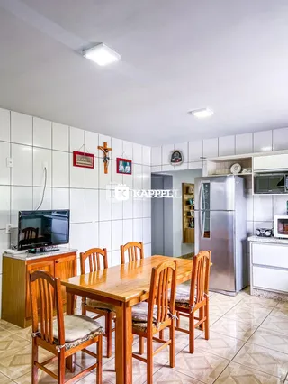 Uma foto de uma sala de jantar com mesa de madeira e cozinha.