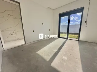 Ambiente interno com piso de concreto e porta de vidro que dá para um jardim.