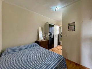 Quarto com cama de casal e parede branca.
