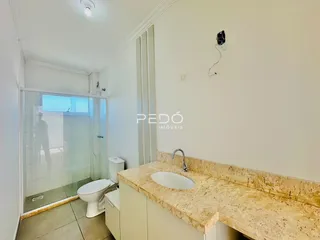 Imagem de um banheiro com box de vidro e pia de granito.