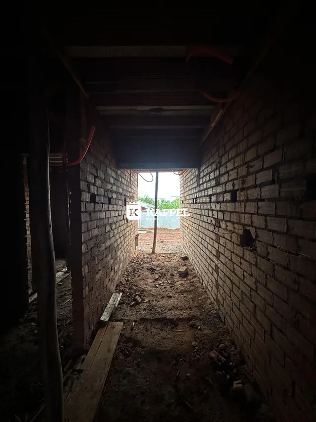 Corredor estreito de tijolos em uma área de construção com piso de terra.