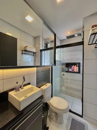 Banheiro moderno com box de vidro e revestimento claro.