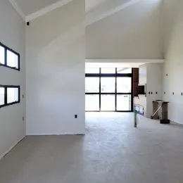 Ambiente interno amplo com paredes brancas e grande janela.