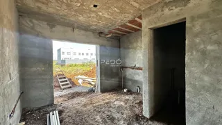 Interior de uma área em construção com paredes de concreto expostas e uma abertura para o exterior.