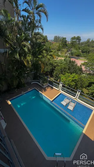 Uma foto aérea mostra uma piscina externa com vista para a vegetação exuberante.