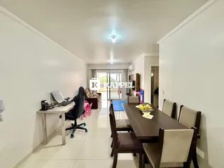 Uma sala de jantar com mesa de madeira escura e cadeiras, com um ambiente claro e bem iluminado.