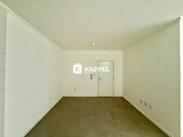Um corredor interno com paredes brancas e piso de cerâmica.