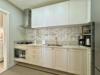 Cozinha moderna com armários brancos e revestimento de azulejos brancos.