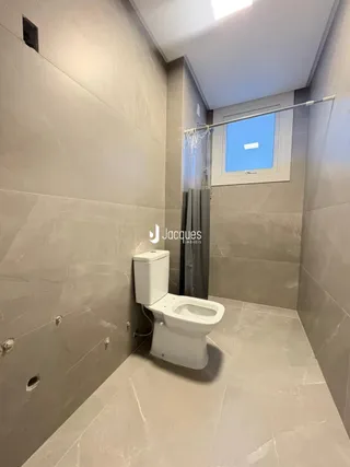 Banheiro com piso de cerâmica e paredes revestidas em tom neutro.