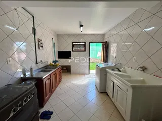 Foto interna de um banheiro com azulejos brancos e bancada de madeira.