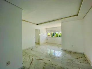 Ambiente interno amplo com piso de mármore polido e paredes brancas.
