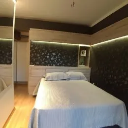 Quarto com cama de casal e cabeceira em parede decorada.