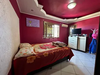 Quarto com paredes rosa e cama de casal em um imóvel no Brasil.