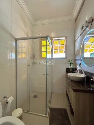 Foto interna de um banheiro com box de vidro e louças sanitárias.