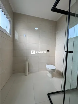 Foto de um banheiro com revestimento de azulejos brancos e box de vidro.